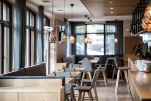 um restaurante com mesas e cadeiras de madeira e janelas em Hotel Landgasthof Weingut Seeperle em Caldaro