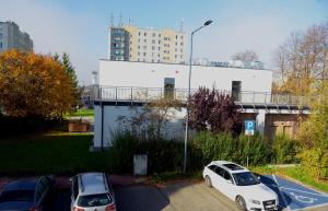 dos autos estacionados en un estacionamiento frente a un edificio en Work & Sleep, en Piaseczno