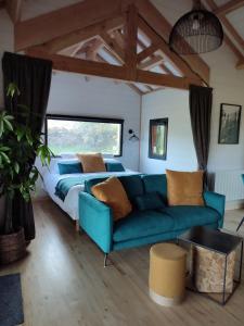 ein Schlafzimmer mit einem blauen Sofa und einem Bett in der Unterkunft Le Domaine des Roches' L in Gommené