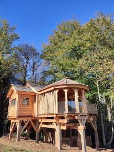 ein Baumhaus auf Baumstämmen in einem Wald in der Unterkunft Le Domaine des Roches' L in Gommené