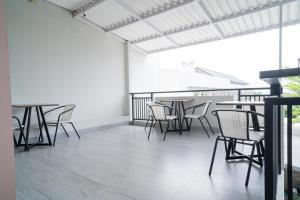 a room with tables and chairs on a balcony at Urbanview Hotel Bubusini Batu by RedDoorz in Batu