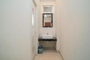 a bathroom with a sink and a mirror at Urbanview Hotel Bubusini Batu by RedDoorz in Batu