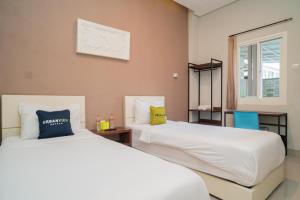 a bedroom with two beds and a window at Urbanview Hotel Bubusini Batu by RedDoorz in Batu