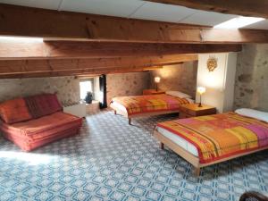 ラグラスにあるMaison de caractère face à l abbaye de lagrasseのベッド2台とソファが備わる広い客室です。