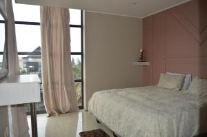 een slaapkamer met een bed en een groot raam bij Accommodation Front - Deluxe 6 Sleeper with Rooftop Pool in Durban +23 foto's