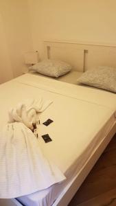 a white bed with two pillows and a blanket on it at Appartamento con piscina e sauna Bissone in Bissone