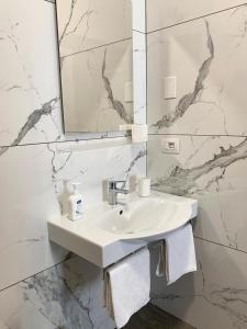 Baño blanco con lavabo y espejo en Residenza La Ciorta, en Nápoles