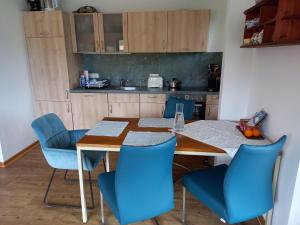 a kitchen with a wooden table and blue chairs at Ferienwohnung Rudis Bergblick in Wallgau