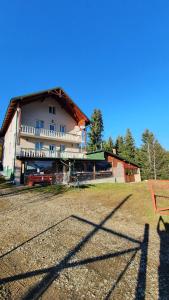 a large white building with a grass field in front of it at CABANA ZIMBROAIA 8 camere -Muntii Bârgăului, Transilvania in Piatra Fantanele