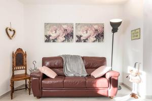 brązowa skórzana kanapa w salonie z różowymi kwiatami w obiekcie La Terrazza suite stile retrò, 90 mq con doccia sauna Wi-Fi terrazzo e garage w Trydencie