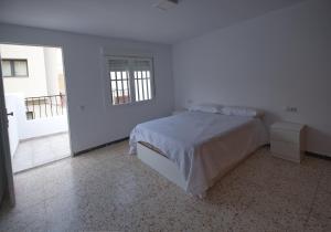 a white bedroom with a bed and a window at Apartamento in Almería