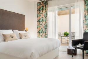 a bedroom with a large white bed and a balcony at Casa Triana 1888 Suites by Época in Seville