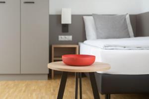 a red bowl on a table in a room with a bed at Brera Serviced Apartments Stuttgart in Stuttgart
