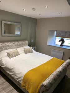 een slaapkamer met een groot bed en een gele deken bij ‘The Retreat” at the Rose @ Crown 