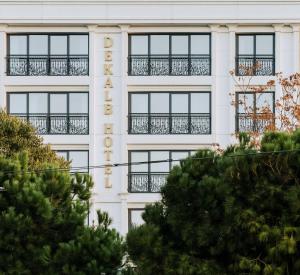a white building with windows and trees in the foreground at Dekalb Hotel in Istanbul