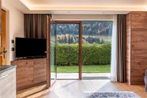 - un salon avec une télévision et une porte coulissante en verre dans l'établissement Villa Erina App C2, à Ortisei
