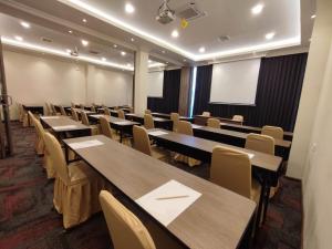 une salle de conférence avec des tables, des chaises et un écran dans l'établissement Kesuma Front One Boutique Palembang, à Palembang