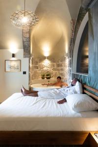 two people laying on a bed with a bath tub at Seaside Apartment Volosko on the beach in Opatija
