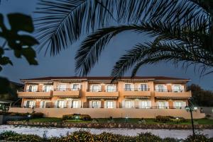 a hotel with a palm tree in front of it at Aristotelis Apartments in Razáta