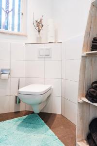 a white bathroom with a toilet and a rug at Hiesli am Goethebrunnen Ferienwohnung in Albersbach