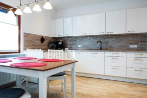 a kitchen with white cabinets and a wooden table at Hiesli am Goethebrunnen Ferienwohnung in Albersbach +4 photos