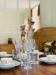 una mesa de madera con vasos y platos. en Appartements Le Tilleul de la Vallée Noble, en Westhalten