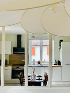 una cocina con armarios blancos y una mesa con sillas. en Appartements Le Tilleul de la Vallée Noble, en Westhalten