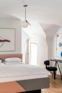 a white bedroom with a bed and a desk at Kai 36 - Hotel zwischen Fels und Fluss in Graz
