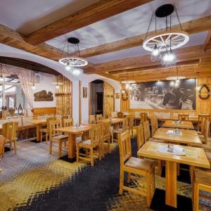 a restaurant with wooden tables and wooden chairs at Penzion Zora Family in Tatranská Lomnica