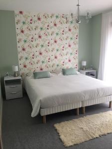 1 dormitorio con 1 cama grande y pared de flores en Maison d’hôtes du Clos de Kério, en Guidel