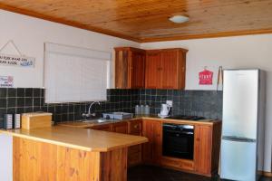 a kitchen with wooden cabinets and a white refrigerator at Malkopbaai Self-Catering in Lambertʼs Bay