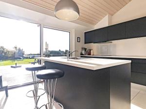 una cocina con armarios negros y una barra con taburetes en 10 person holiday home in Faaborg, en Bøjden