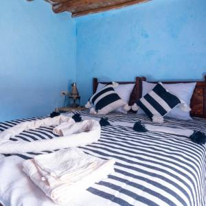 a blue bedroom with a bed with black and white sheets at Atlas Kasbah Lodge in Imlil