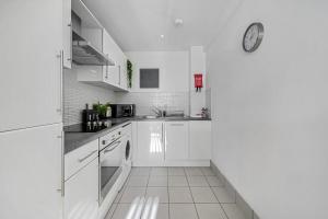 eine Küche mit weißen Schränken und einer Uhr an der Wand in der Unterkunft Host & Stay - Standish Street Abode in Liverpool