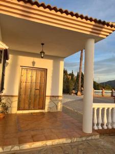 una veranda anteriore di una casa con porta in legno di CasaBlanca Villa Rural con piscina y barbacoa a Viñuela