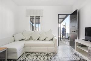 a living room with a white couch and a tv at Casa Pablo in Conil de la Frontera