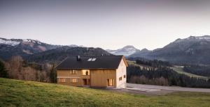 a house on a hill with mountains in the background at HALWINA Hideaway in Sibratsgfäll