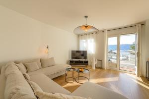 ein weißes Wohnzimmer mit einem Sofa und einem TV in der Unterkunft Centre Veyrier du Lac, Luxueux appartement vue lac Annecy et PISCINE, LLA Selections by Location lac Annecy in Veyrier-du-Lac