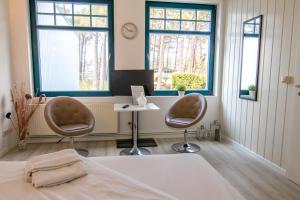 a bedroom with two chairs and a table and two windows at Ferienanlage Zum Knirk in Lubmin