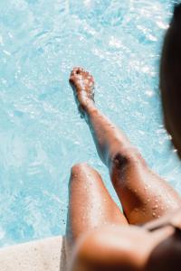 a Personen Beine im Wasser in einem Pool in der Unterkunft Can Vistabella Boutique Resort in Sant Antoni de Portmany