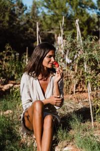 Eine Frau, die im Gras sitzt und einen roten Apfel isst. in der Unterkunft Can Vistabella Boutique Resort in Sant Antoni de Portmany