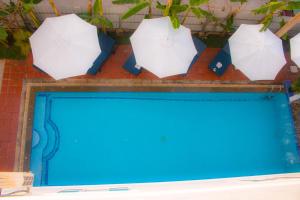 una piscina blu con ombrelloni sopra di essa di The Blanc Residence a Siem Reap