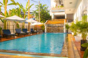 a pool in a hotel with chairs and umbrellas at The Blanc Residence in Siem Reap