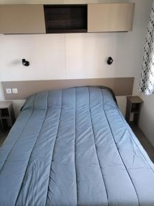 a bed in a room with a blue blanket at Mobilhome 6/8 personnes Piriac sur Mer in Piriac-sur-Mer