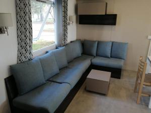 um sofá azul numa sala de estar com uma janela em Mobilhome 6/8 personnes Piriac sur Mer em Piriac-sur-Mer