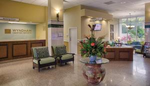 un vestíbulo con una zona de espera con sillas y un jarrón con flores en Club Wyndham Santa Barbara, en Pompano Beach