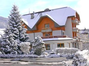 una casa cubierta de nieve con un árbol de Navidad en Hotel Burgstallerhof, en Feld am See