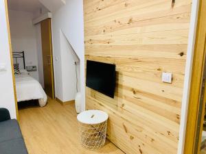 Habitación con pared de madera y TV de pantalla plana. en Acogedor estudio en Pontedeume, en Puentedeume