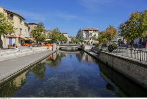eine Brücke über einen Fluss in einer Stadt in der Unterkunft Maison de village façon Loft, avec cour et airco, dans le centre historique in LʼIsle-sur-la-Sorgue