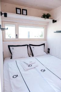 ein weißes Bett in einem kleinen Zimmer mit zwei Fenstern in der Unterkunft Buqez resort Drage, villa Vita 50 in Pakoštane
